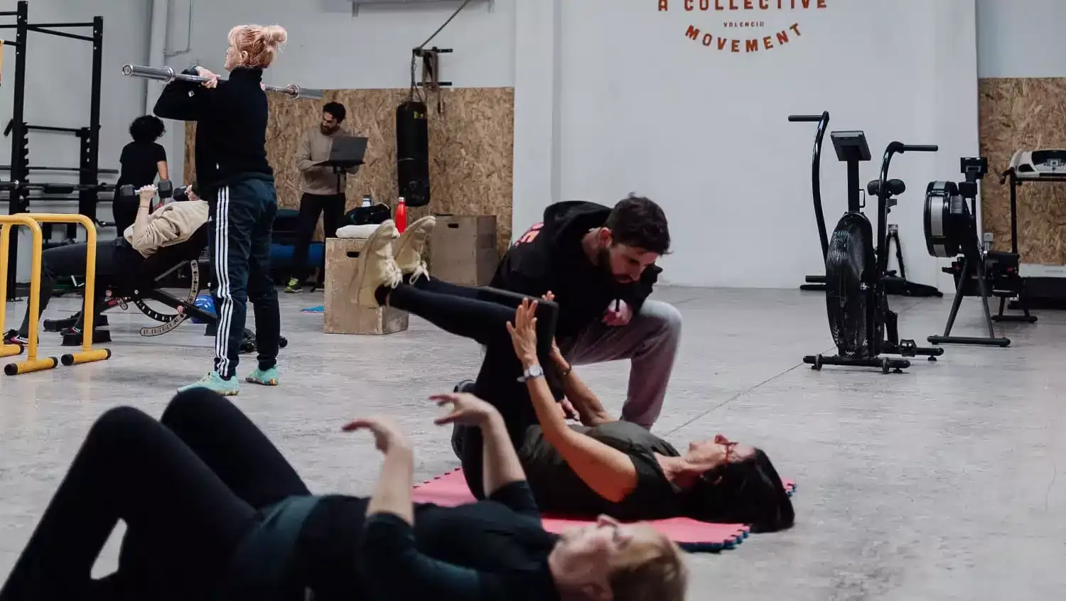 Entrenador de CORE asistiendo un ejercicio en colchoneta durante una sesión de readaptación